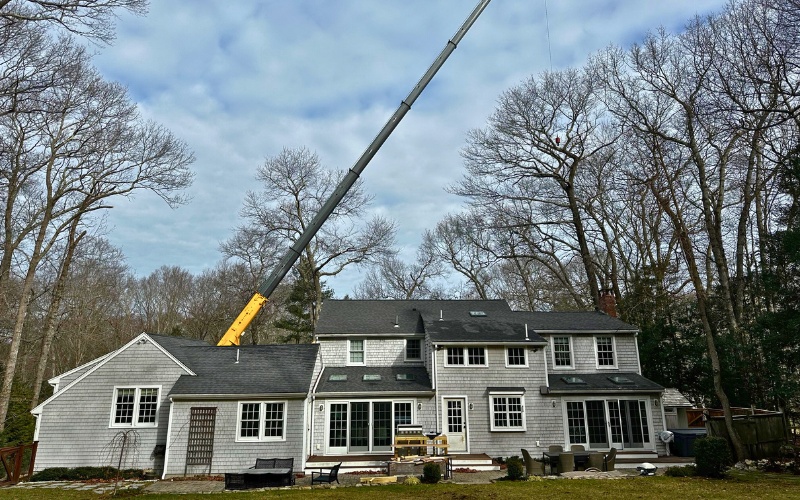 The Top Notch Tree crane positioned near a South Shore home during winter tree removal, showing specialized equipment needed for emergency removal.