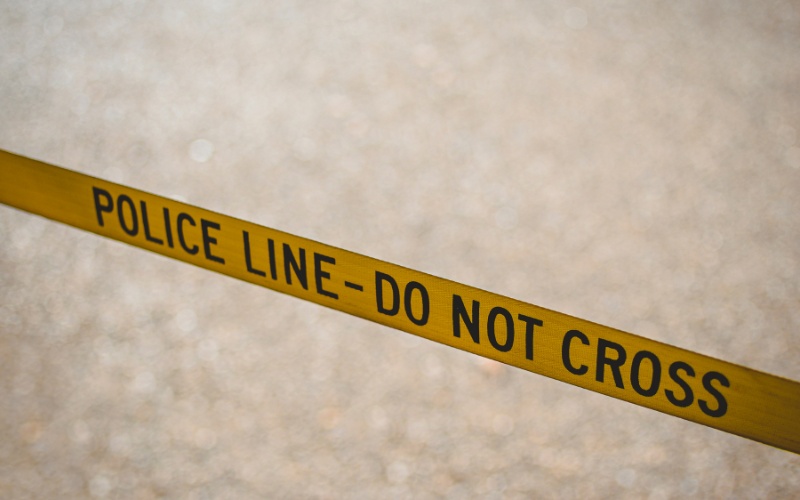 Yellow police line tape establishes a safety perimeter during tree removal operations.