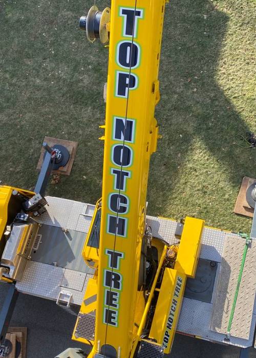 A top view on one of Top Notch Tree's yellow cranes displaying the logo on it.