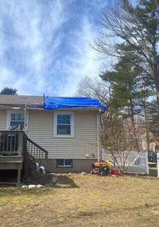 A roof temporarily covered by a tarpaulin after a tree that fell on top of it was removed by Top Notch Tree.